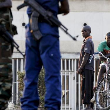 Residents look on as police and soldiers guard a voting station in the Burundian capital, Bujumbura, during presidential elections on July 21, 2015.
