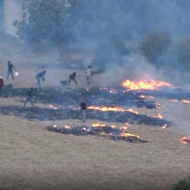 Conforme caen las llamas de los cohetes incendiarios, nubes de humo cubren las tierras de cultivo en el oeste de Idlib, Siria, el 30 de julio de 2018.